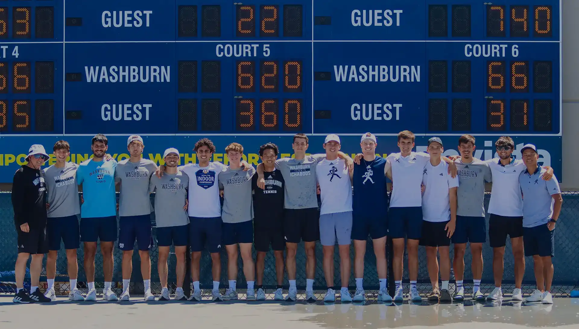 Men's tennis team lined up on court with scoreboard behind