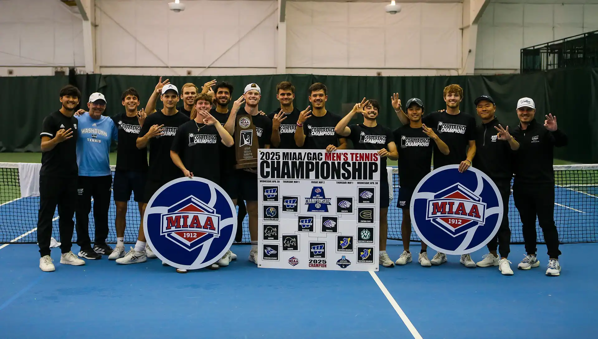 Men's tennis team lined up on court holding MIAA Championship sign and smiling