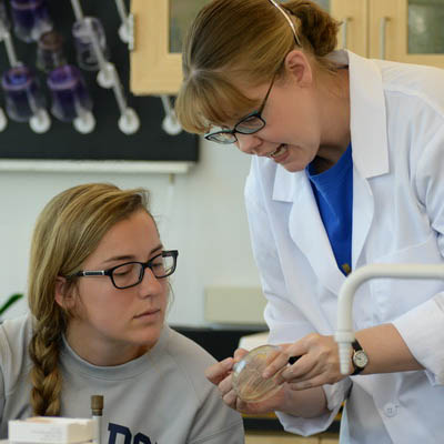 A biology professor explains something to a student in class.