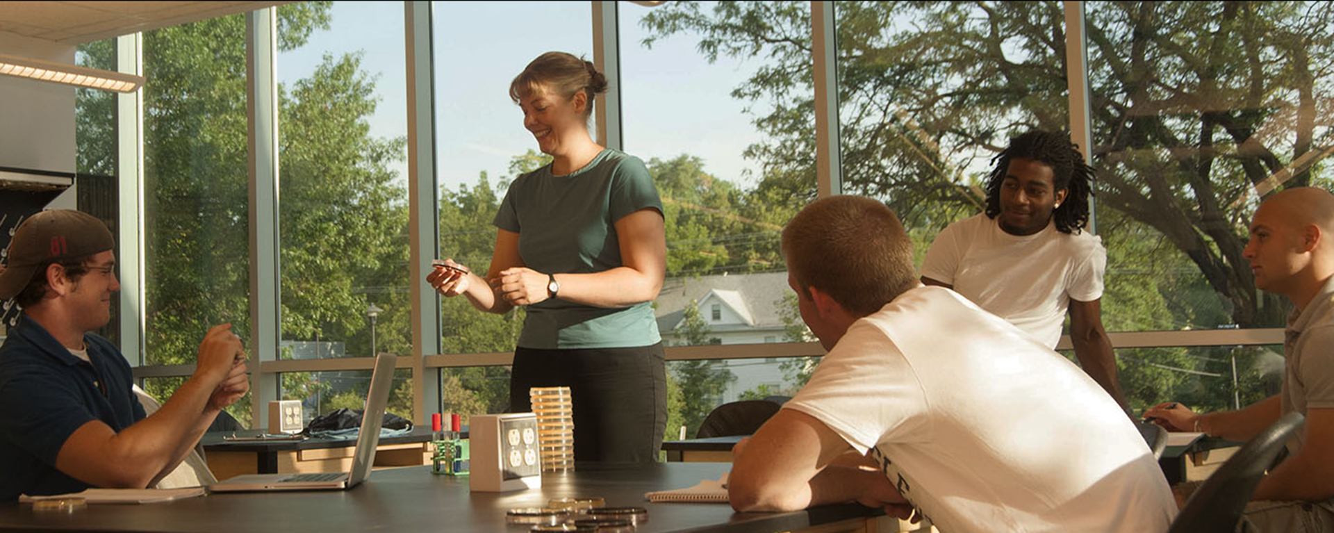 A biology class is held in a classroom with large windows featuring the outdoors.