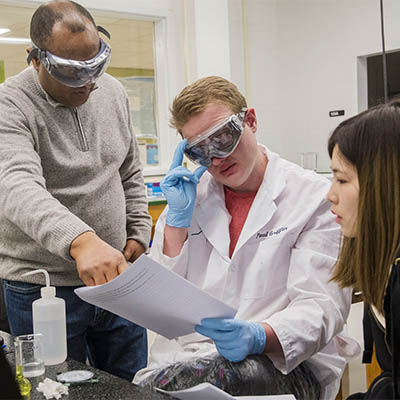 A professor explains something to students in a lab