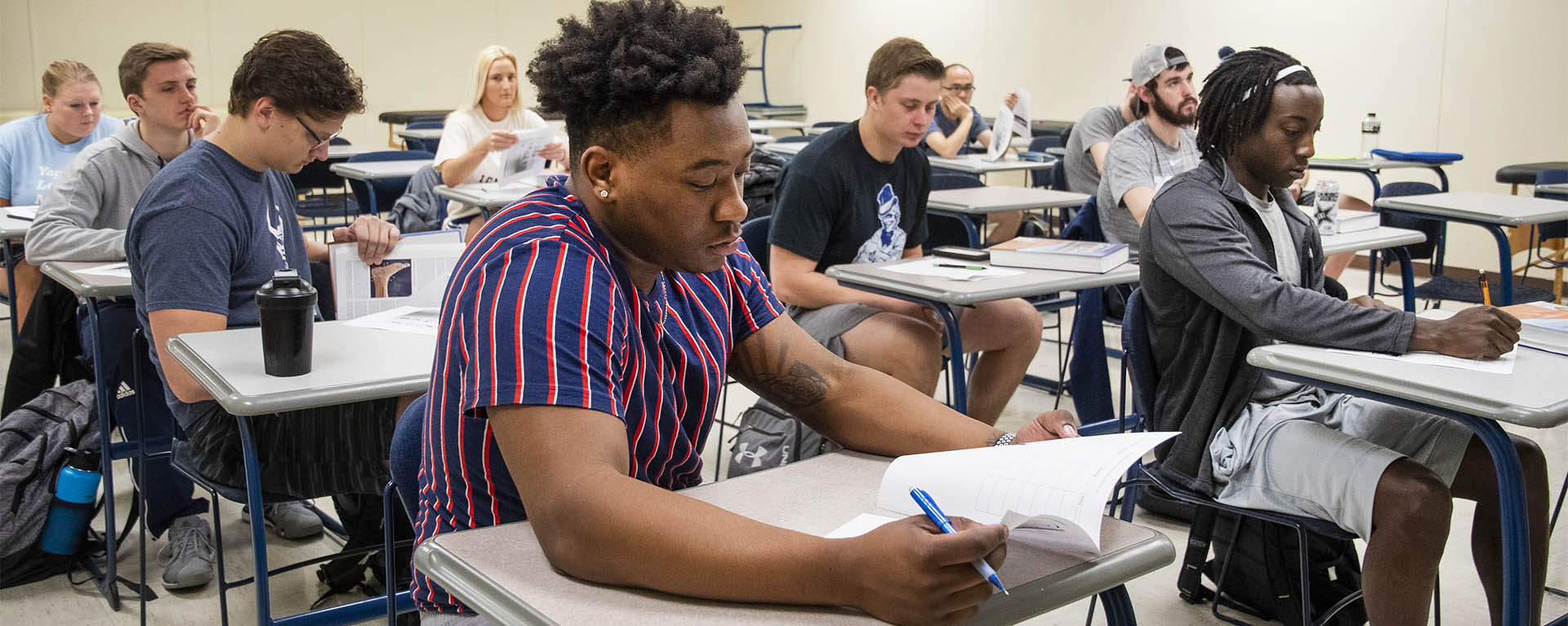 A kinesiology flips through his textbook while listening to a class lecture.