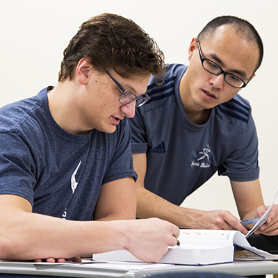 Two kinesiology students study a textbook.