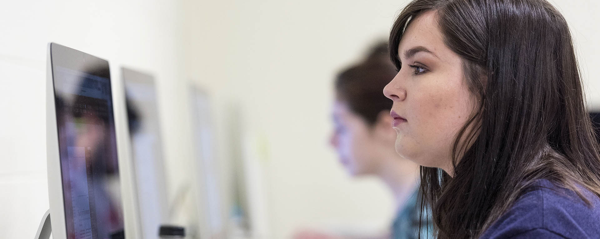 A public relations student studies her graphic on the screen.