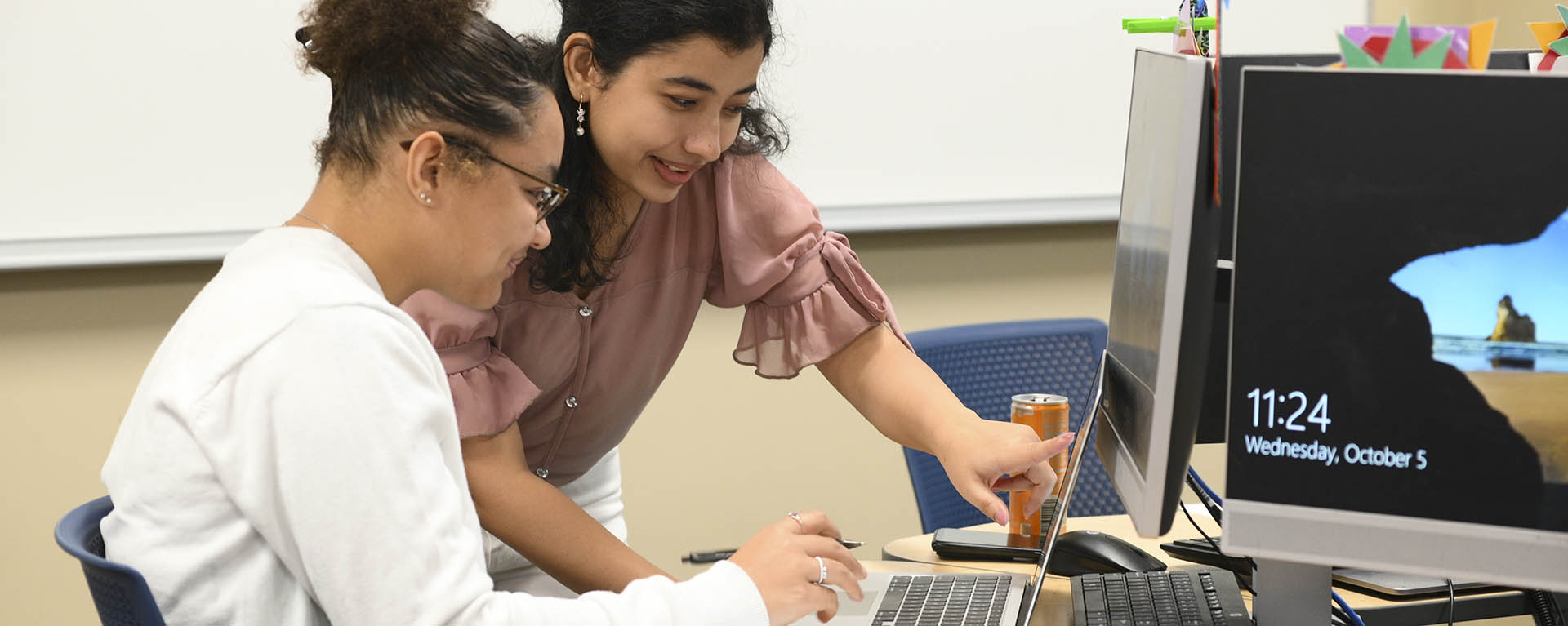 A student helps another student with a math assignment.