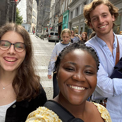 Two Washburn students smile while standing in the rain in front of Sacred Heart Church in France.