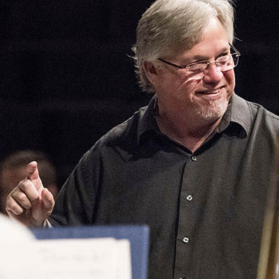 music professor smiling while conducting in front of students
