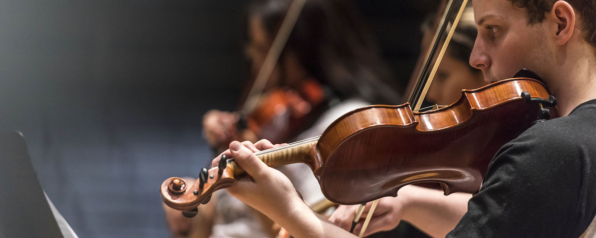 A student plays a violin during ensemble practice.