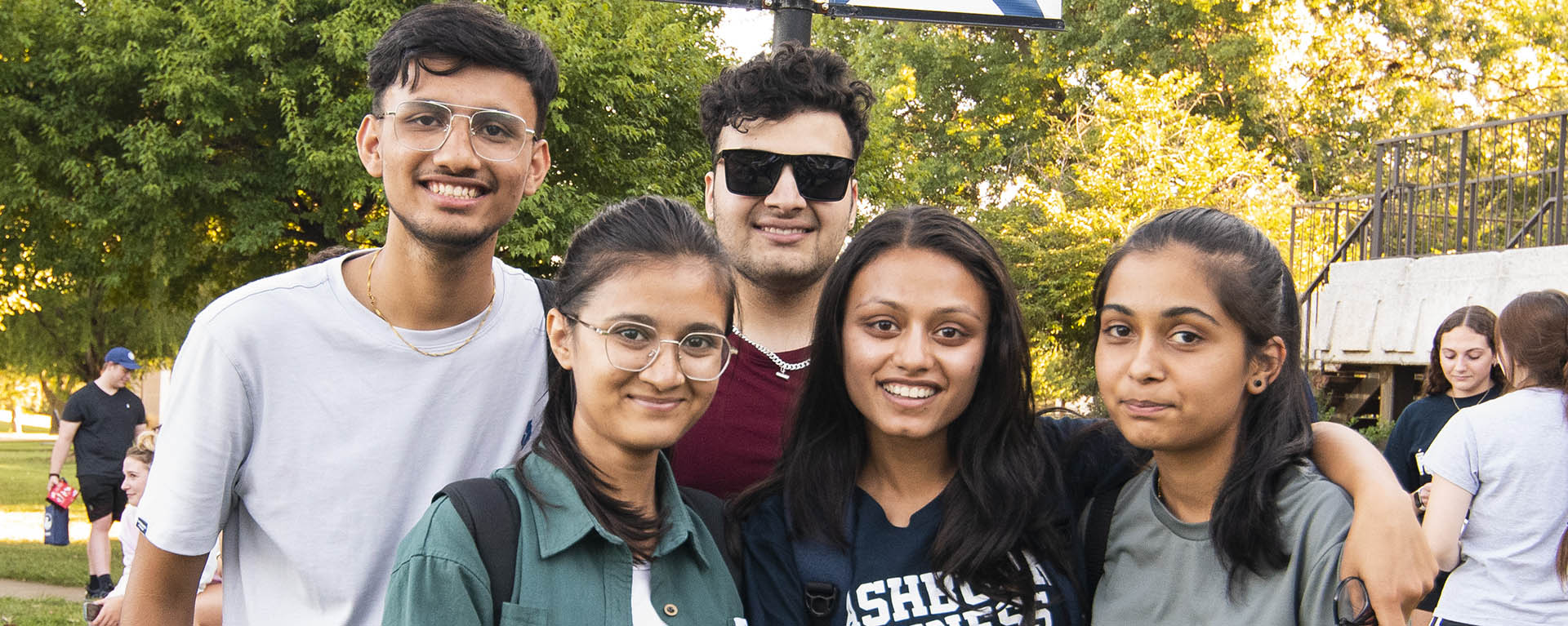 four students outside smiling at camera