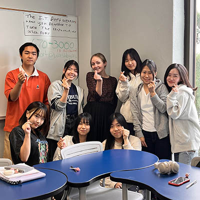 Two students smile and give a thumbs up