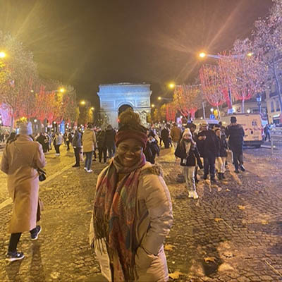 Noel smiling in front of lit up trees