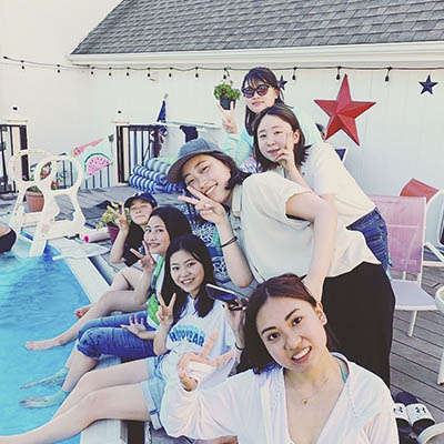 Students smile and pose for a photo around a pool.