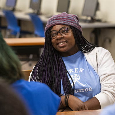 student smiling and sitting at table with laptop