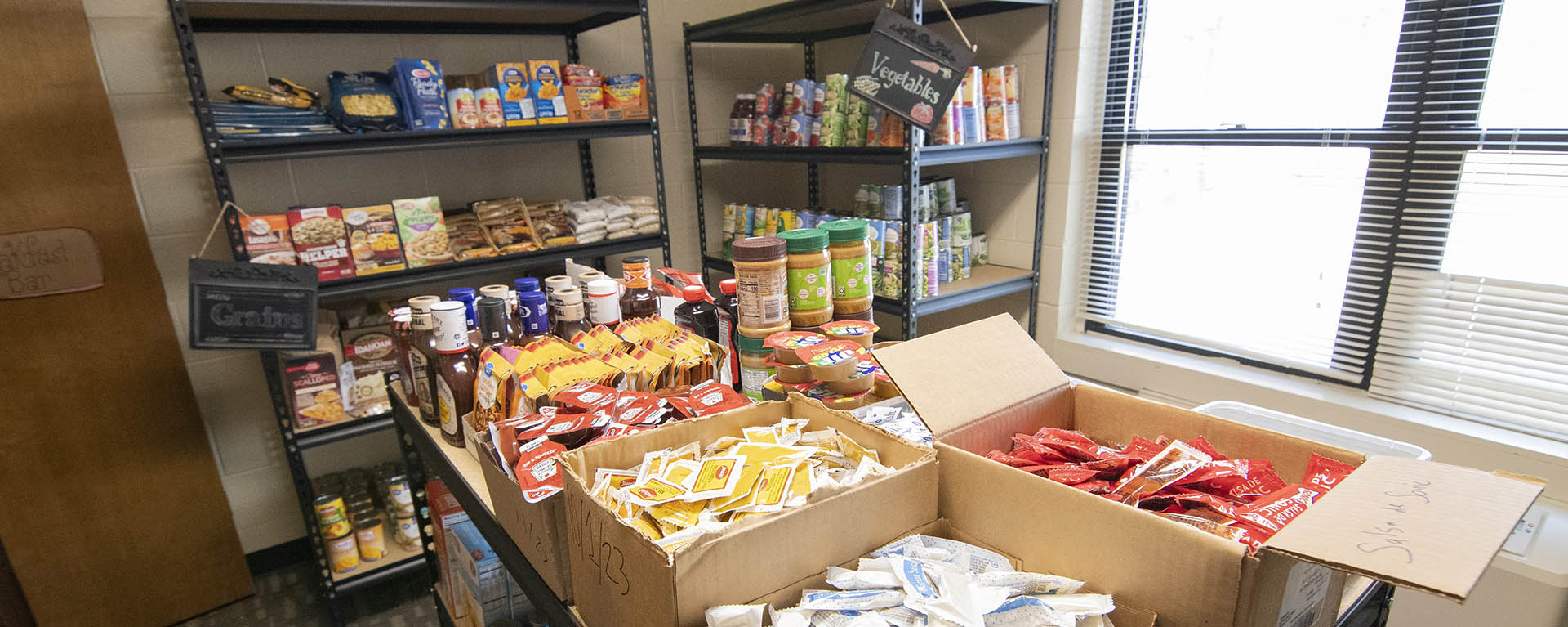 Boxes and cans of food line shelves in a small room.