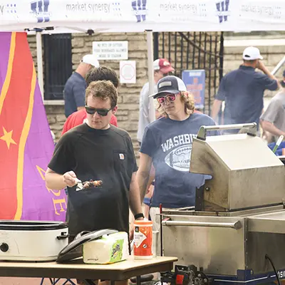 A fraternity member grills during a tailgate.
