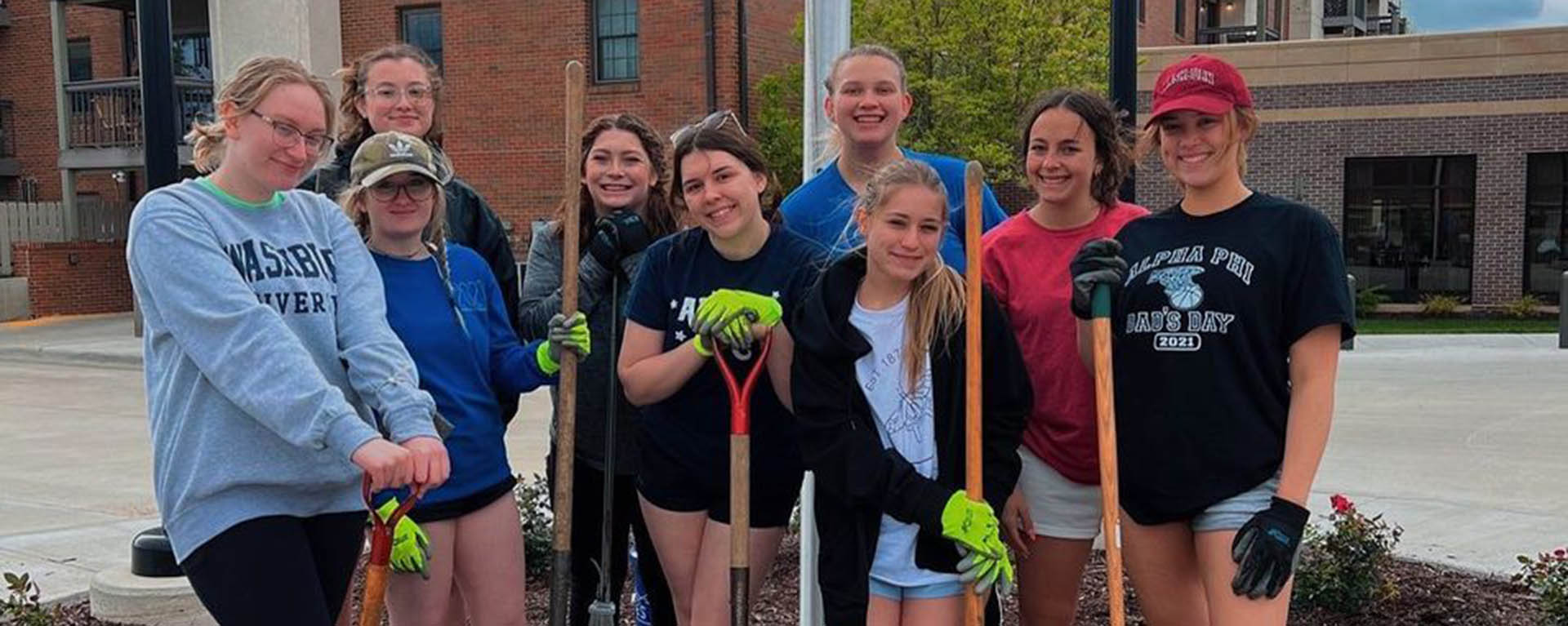 Students smile while posing with shovels at the Big Event.