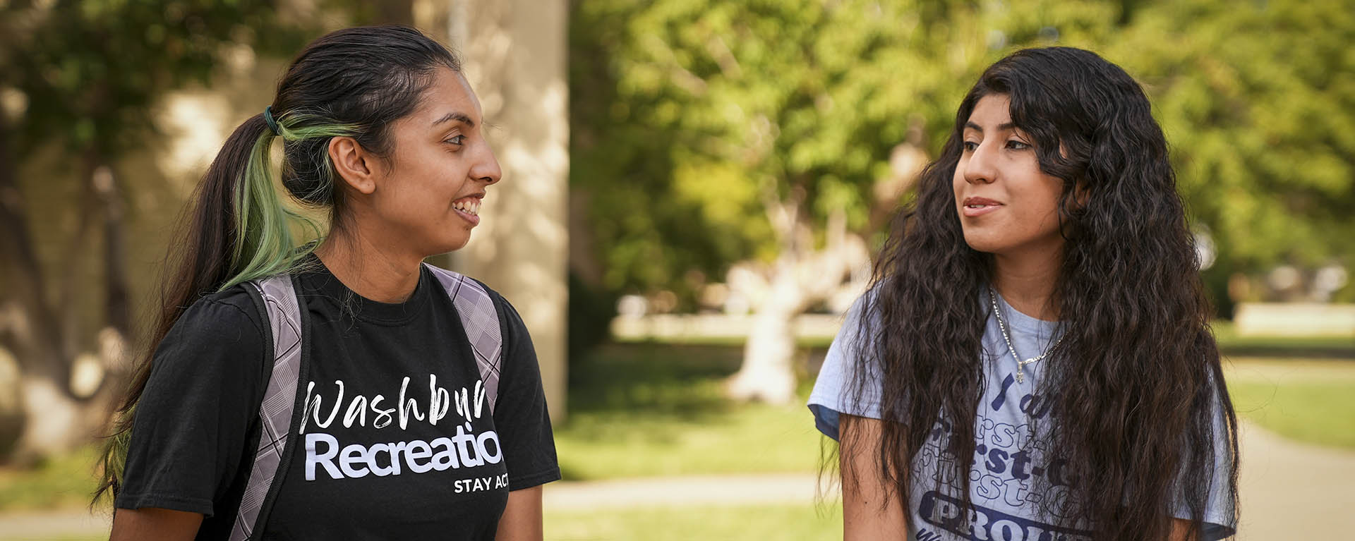 Washburn students smile while walking on campus.