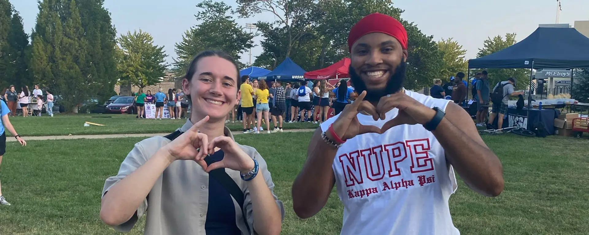 Two Washburn students smile and hold their hands in the shape of a heart.