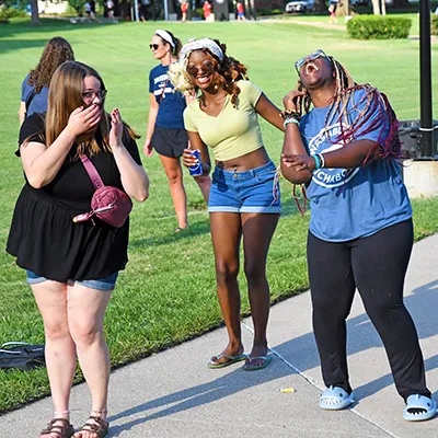 Students laugh together while attending an event outside on campus.