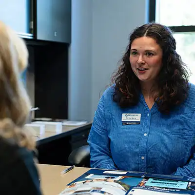 A recruiter smiles while meeting with a student on a visit.