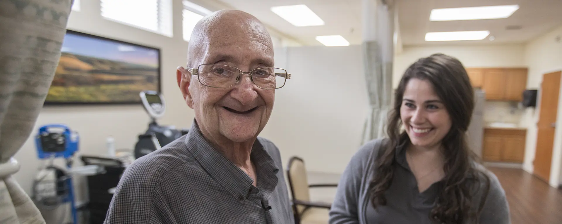 A patient smiles while a health care leader helps them in a clinical setting.