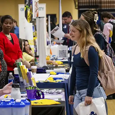 student at employer table talking with employers at career fair