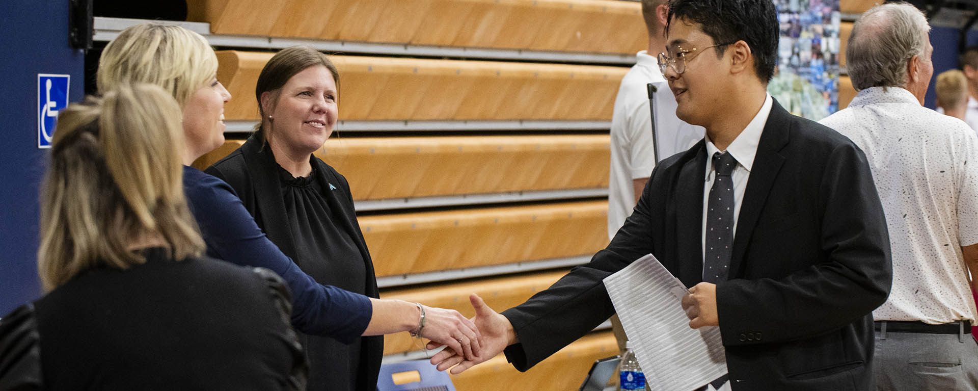 A student shakes hands with a potential employer at a career fair.