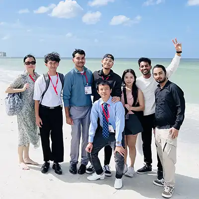 cis students pose on Florida beach with ocean and blue sky behind