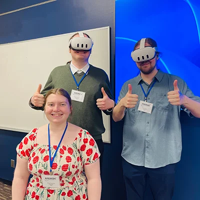 Students pose for a photo while wearing virtual reality head sets.