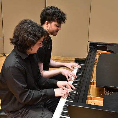 two students playing piano in class
