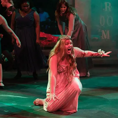 A student on stage in a costume that looks like an angel.