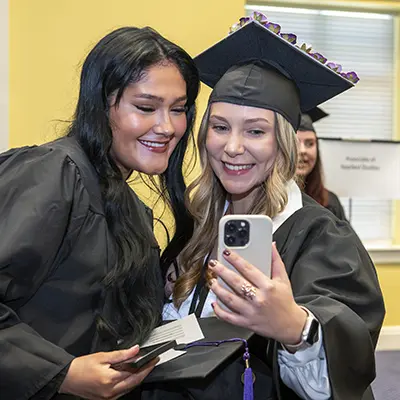 Graduates smile and take a selfie.