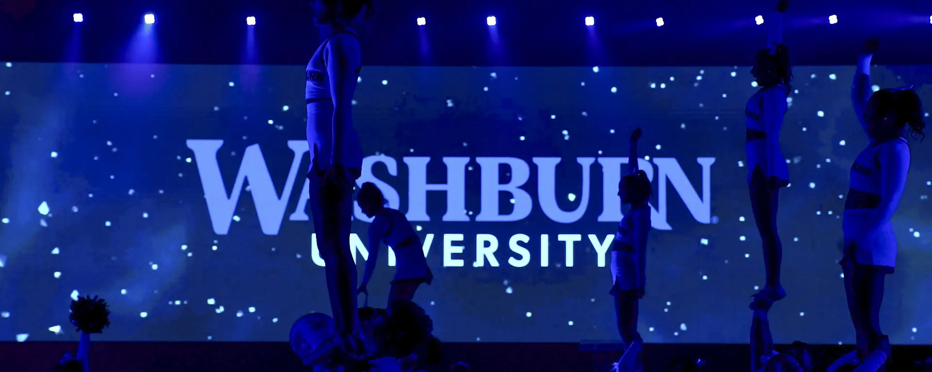 Washburn cheerleader silhouettes in front of the Washburn logo.