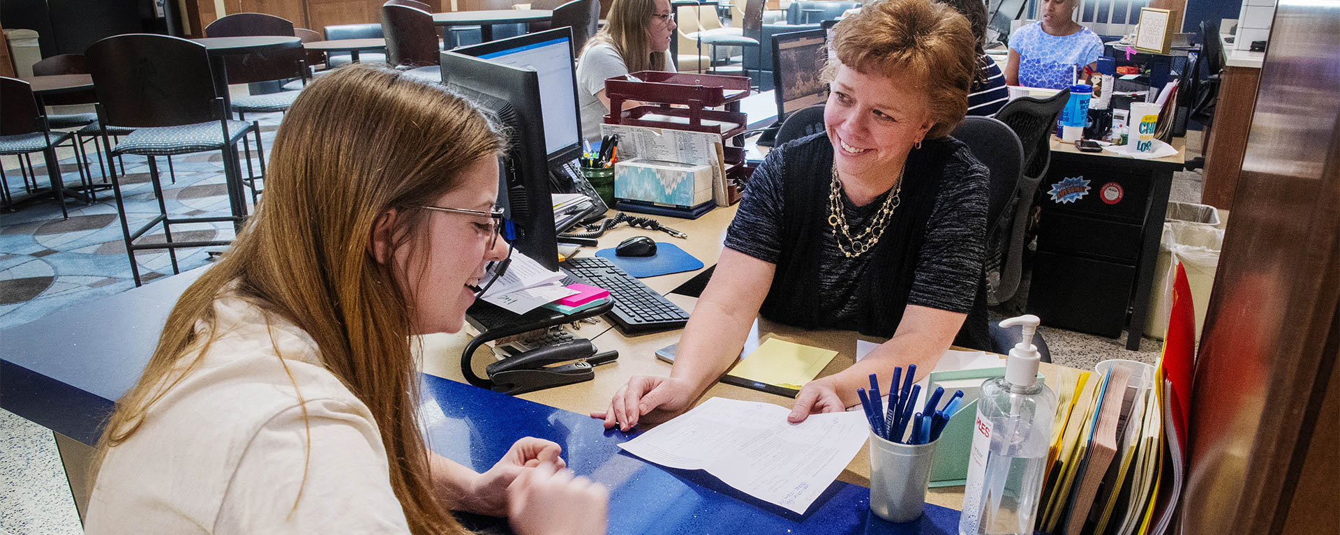 A staff member smiles while helping a student at the Student One Stop.