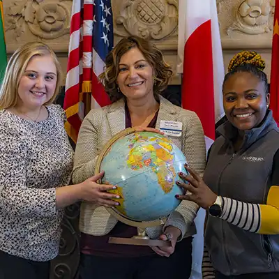 three Washburn employees with a globe smiling