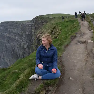 student sitting on Moher cliffs in Ireland
