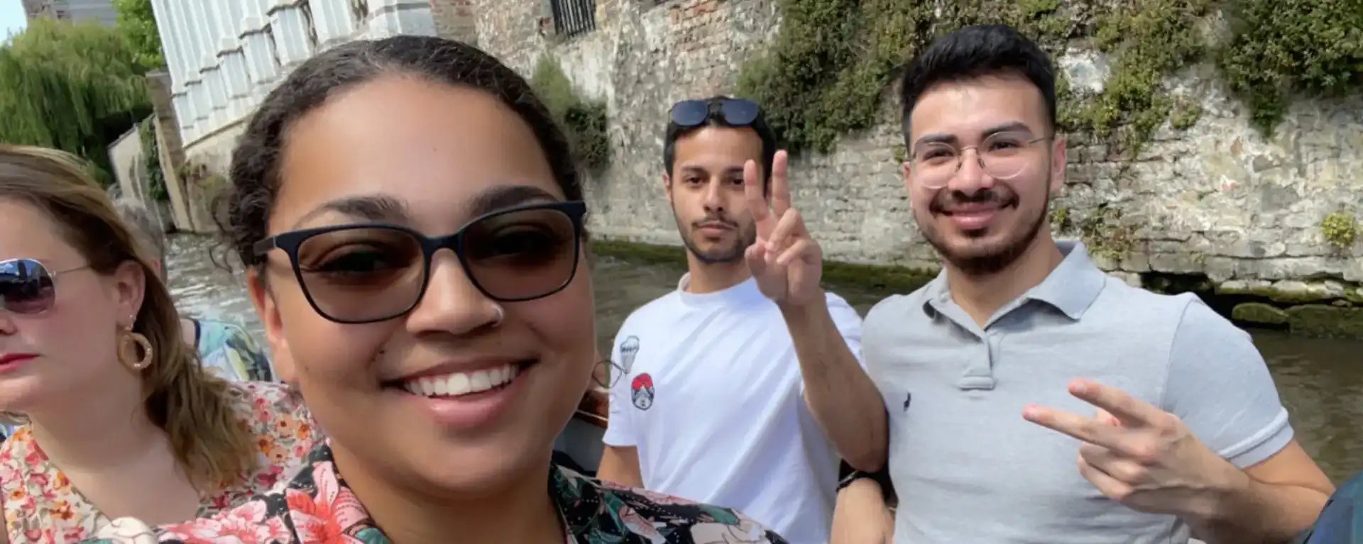 3 students smiling for camera giving peace sign