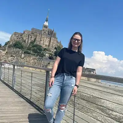 student in front of waterfront castle in France