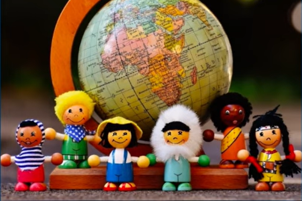 small toys that look like international children grouped in front of a small globe